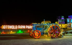 A traditional tractor covered in Christmas lights and a sign in the background saying, "Cotswold Farm Park".