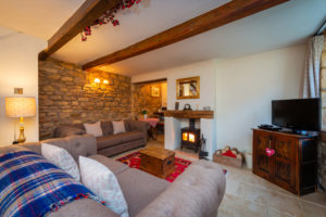 The lounge of Honeypot Cottages ideal romantic retreat with exposed beams, dark wood furniture and a traditional wood fire.